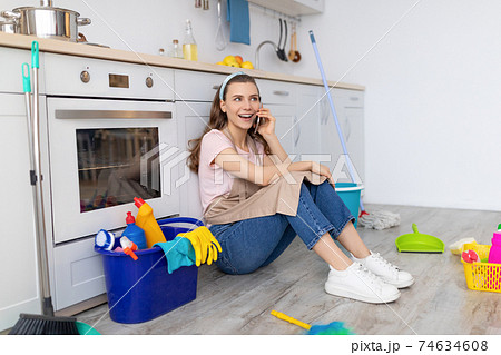 Cheerful woman speaking on cellphone during break from housework, enjoying phone conversation with friend at kitchen Cheerful woman speaking on cellphone during break from housework, enjoying phone conversation with friend at kitchen 74634608