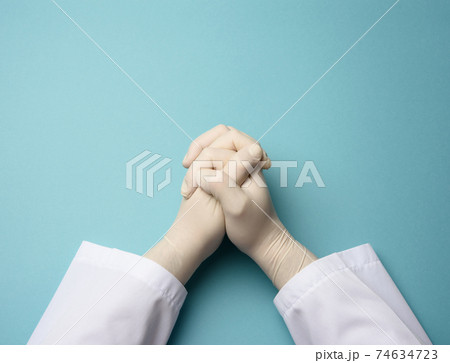 two male hands in white latex gloves, doctor's palms on a blue background in a prayer position two male hands in white latex gloves, doctor's palms on a blue background in a prayer position 74634723