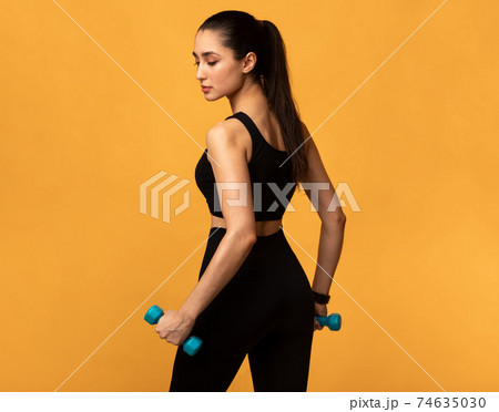 Sporty Woman Posing With Dumbbells Isolated On Orange Background 74635030