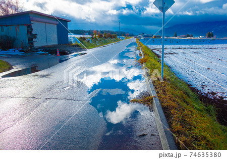 雨上がりの道路の水たまりに映った雲の写真素材 [74635380] - PIXTA
