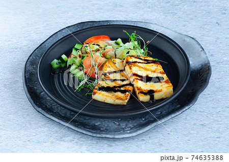 Slices of grilled halloumi cheese with vegetable salad, tomatoes and cucumber 74635388