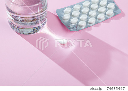Water glass, blister with medical pills, tablets, vitamins on pink background 74635447