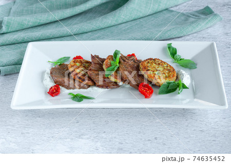 Fried grilled slices of beef fillet with vegetable zucchini and cabbage pancakes Fried grilled slices of beef fillet with vegetable zucchini and cabbage pancakes 74635452