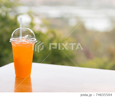 Glass of orange juice on the table outdoor Glass of orange juice on the table outdoor 74635504