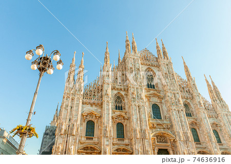 Famous church Milan Cathedral Duomo di Milano with Gothic spires and white marble statues. Top tourist attraction on piazza in Milan Lombardia Italy. Wide angle view of old Gothic architecture and art Famous church Milan Cathedral Duomo di Milano with Gothic spires and white marble statues. Top tourist attraction on piazza in Milan Lombardia Italy. Wide angle view of old Gothic architecture and art 74636916