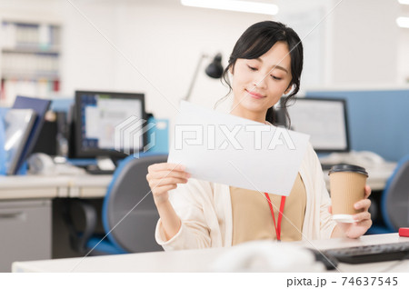 オフィスでコーヒーを飲みながら仕事するビジネスウーマンの写真素材