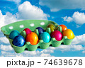 Colorful eggs in a open carton box on blue sky background.eggs flies over whites clouds. 74639678