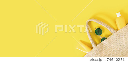 Summer yellow banner flatlay on colorful background with wicker straw bag, tubes and bottle with sunscreen, green sunglasses. Hard shadows and light. Top view. Flat lay. Trend style. Copyspace. 74640271