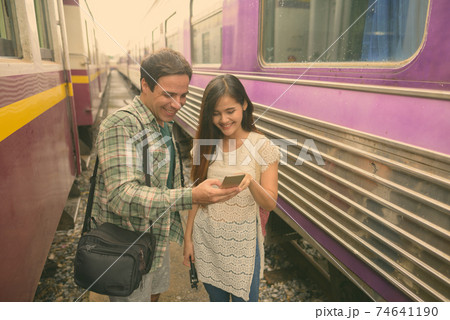 Persian tourist man and young Asian tourist woman together at the railway station Persian tourist man and young Asian tourist woman together at the railway station 74641190