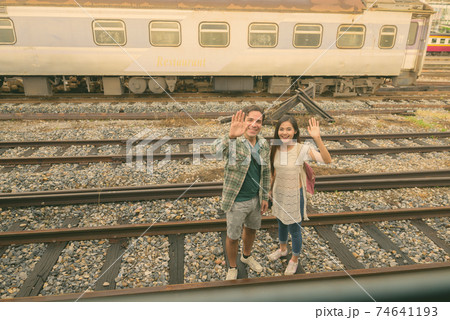 Persian tourist man and young Asian tourist woman together at the railway station Persian tourist man and young Asian tourist woman together at the railway station 74641193