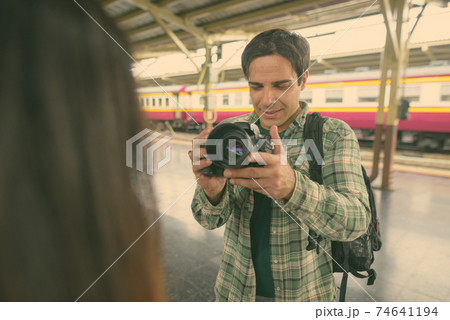 Persian tourist man and young Asian tourist woman together at the railway station Persian tourist man and young Asian tourist woman together at the railway station 74641194