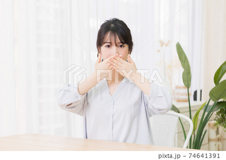 口を隠すジェスチャーをする若い女性 74641391