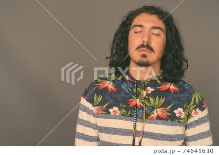 Handsome man with curly hair and mustache against gray background 74641630