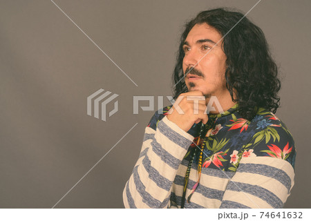 Handsome man with curly hair and mustache against gray background 74641632