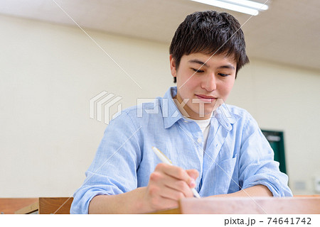 大学の教室で講義を受け板書をノートに写す男子大学生　色味自然光 74641742