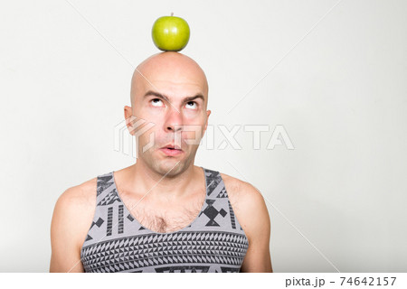 Portrait of bald man with apple on top of head 74642157