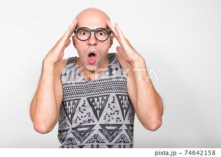 Portrait of bald nerd man with eyeglasses looking shocked 74642158