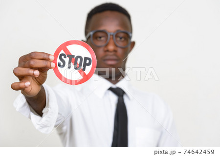 Face of young African businessman holding stop sign Face of young African businessman holding stop sign 74642459
