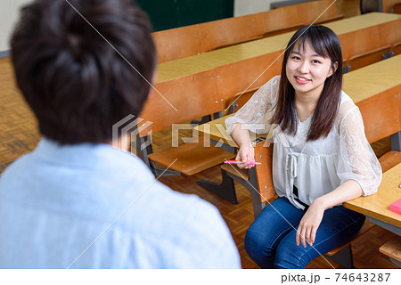 大学の教室で話し合う男女の大学生 カメラ目線の写真素材