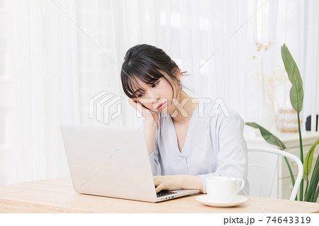 部屋でノートパソコンを使いながら悩む女性 74643319