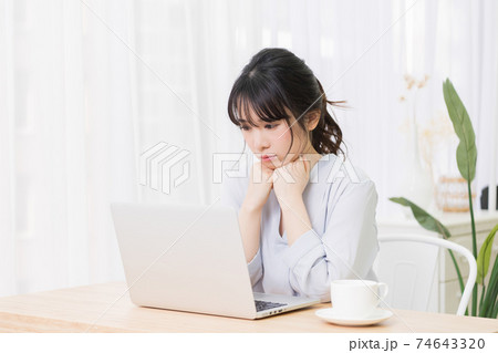 部屋でノートパソコンを使いながら悩む女性 部屋でノートパソコンを使いながら悩む女性 74643320
