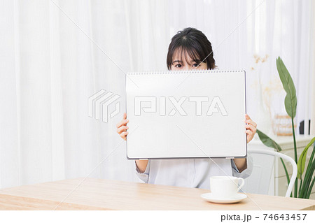 部屋で大きいスケッチブックを持つ若い女性 部屋で大きいスケッチブックを持つ若い女性 74643457