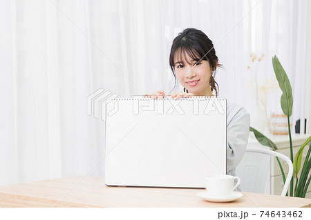 部屋で大きいスケッチブックを持つ若い女性 74643462