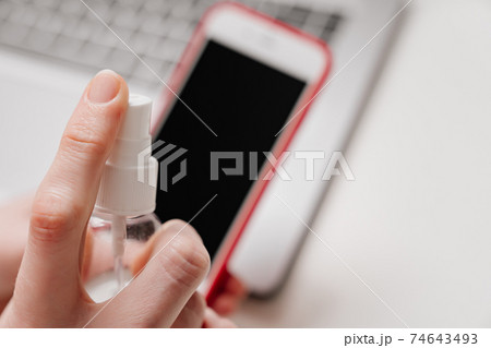 Smartphone screen is treated with antiseptic or cleansing spray for electronics. Smartphone screen is treated with antiseptic or cleansing spray for electronics. 74643493