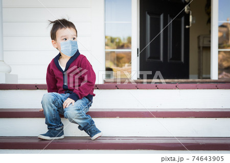 Melancholy Lonely Mixed Race Boy On Front Porch Wearing Medical Face Mask During the Coronavirus Pandemic Melancholy Lonely Mixed Race Boy On Front Porch Wearing Medical Face Mask During the Coronavirus Pandemic 74643905