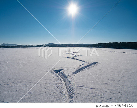 Amazing cutouts of ice skater tracks in dusty snow. View of open frozen lake or pond Amazing cutouts of ice skater tracks in dusty snow. View of open frozen lake or pond 74644216