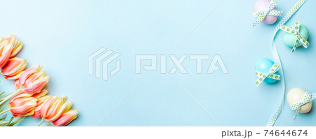 Easter border. Colorful egg with tape ribbon, spring tulips, feathers on pastel blue background in Happy Easter decoration. Banner, top view. Easter border. Colorful egg with tape ribbon, spring tulips, feathers on pastel blue background in Happy Easter decoration. Banner, top view. 74644674