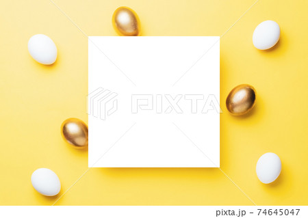 Easter egg hunt. Golden, white colour egg on pastel yellow background in Happy Easter decoration. Traditional design in top view. Easter egg hunt. Golden, white colour egg on pastel yellow background in Happy Easter decoration. Traditional design in top view. 74645047