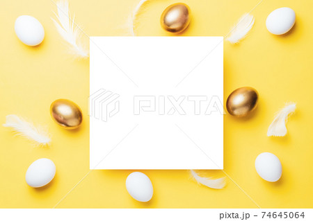 Easter border. Golden, white colour egg on pastel yellow background in Happy Easter decoration. Flat lay, top view. 74645064