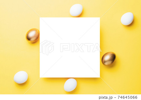 Easter holiday. Golden, white colour egg on pastel yellow background in Happy Easter decoration. Spring holiday top view with copy space. 74645066