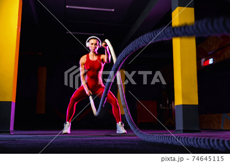 Fitness woman using training ropes for exercise at gym. Athlete 74645115