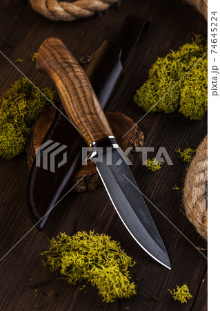 Hunting knife made of damascus steel on wooden background 74645224