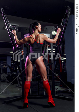 Athletic sexy woman doing exercise using machine in gym - back v Athletic sexy woman doing exercise using machine in gym - back v 74645401