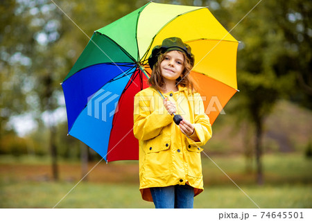Happy funny child girl with multicolor umbrella in rubber boots at autumn park Happy funny child girl with multicolor umbrella in rubber boots at autumn park 74645501