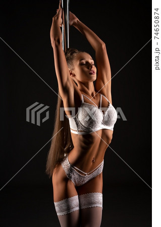 Flexible woman in lingerie near pole in studio Flexible woman in lingerie near pole in studio 74650874