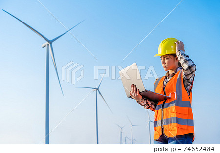 stressed female engineer having problem to working with laptop computer against wind turbine farm stressed female engineer having problem to working with laptop computer against wind turbine farm 74652484