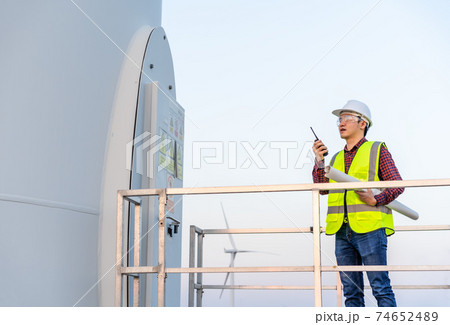 male engineer using walkie talkie to checking system against wind turbine farm male engineer using walkie talkie to checking system against wind turbine farm 74652489