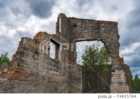 Destroyed wall. Fragments of the wall against the sky. Ruins of houses. Summer day 74655764