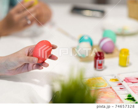 Female hold holding pink egg while painting Easter egg for Easter festival Female hold holding pink egg while painting Easter egg for Easter festival 74657328