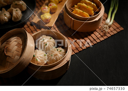 Bamboo steamers with dumplings and pork bun on dinning table in Chinese restaurant Bamboo steamers with dumplings and pork bun on dinning table in Chinese restaurant 74657330
