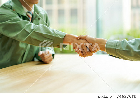 握手をする作業服にネクタイ姿の会社員 74657689