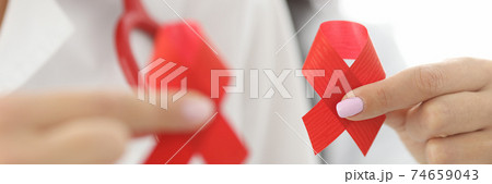 Doctors in white coats hold red ribbon in their hands. Doctors in white coats hold red ribbon in their hands. 74659043