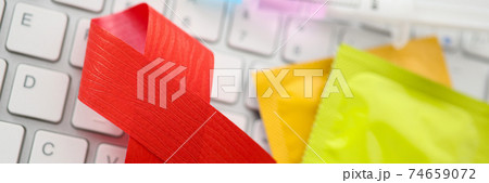 Two condoms and red ribbon on keyboard closeup Two condoms and red ribbon on keyboard closeup 74659072