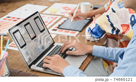 Cropped image of two people is using a computer laptop with an interface icon on the screen at the wooden table. 74660121