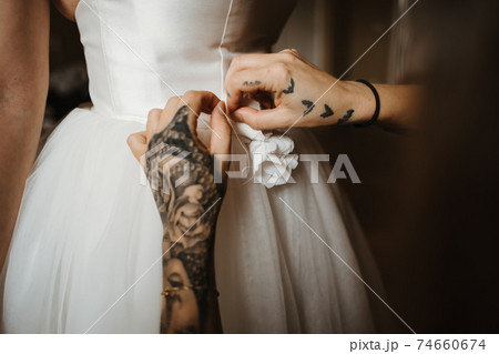 photo of a friend helping a bride to wear her dress 74660674