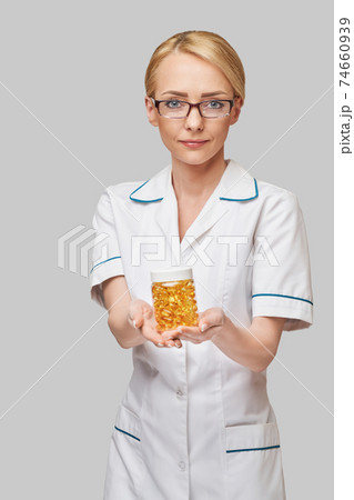 Health care and diet concept - doctor nutritionist or cardiologist holding fish oil in capsules for vitamin D and omega-3 fatty acids Health care and diet concept - doctor nutritionist or cardiologist holding fish oil in capsules for vitamin D and omega-3 fatty acids 74660939